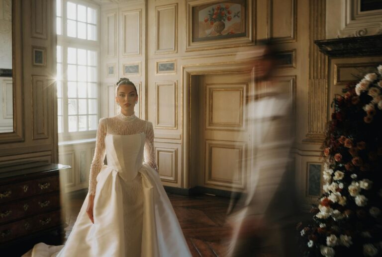 Elegant bride standing in luxurious French-style interior with natural light.
